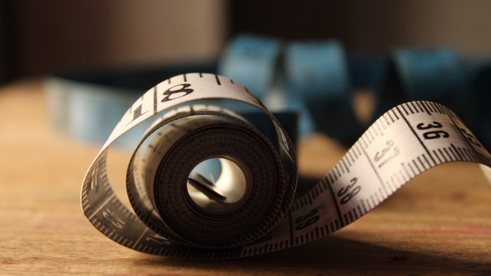 Rolled tailor's tape measure with centimeter markings on a wooden table, atmosphere photo, not a product photo