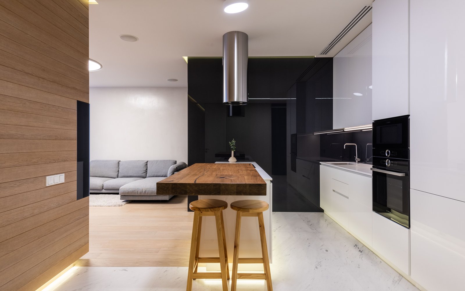 Open studio with two wooden backless stools at a wood-top island and sofa behind, atmosphere photo, not a Flash or Lavish listing photo
