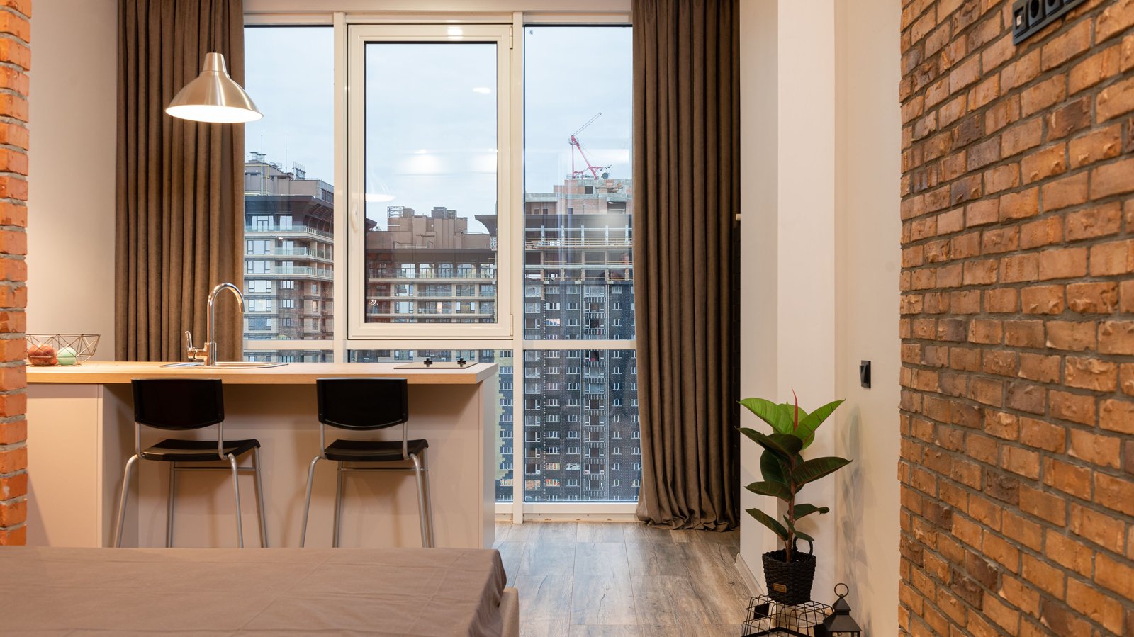 Studio apartment with a bed, a kitchen counter and two counter stools by the window, atmosphere photo, not a product pick